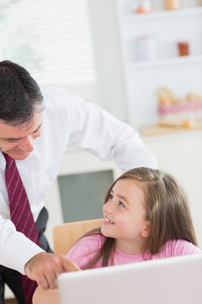 Padre che punta al portatile con figlia sorridendo a lui