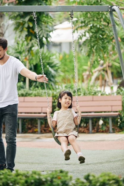 Padre che spinge figlia seduta sull'altalena