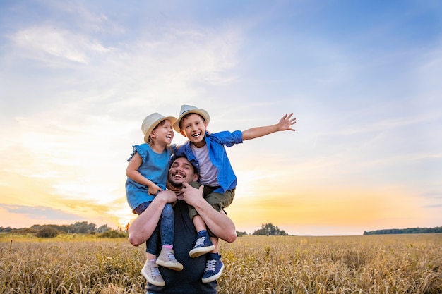 padre che tiene i suoi due figli in un campo di grano