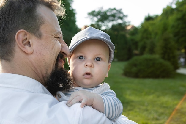 padre che tiene in braccio il figlio su uno sfondo di verde