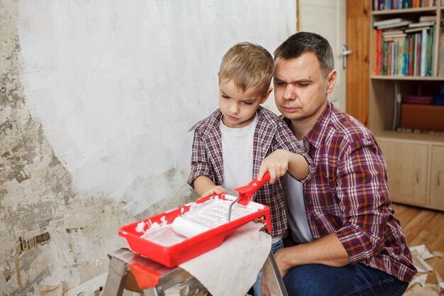 Padre con bambino che ripara stanza insieme e dipinge insieme il muro