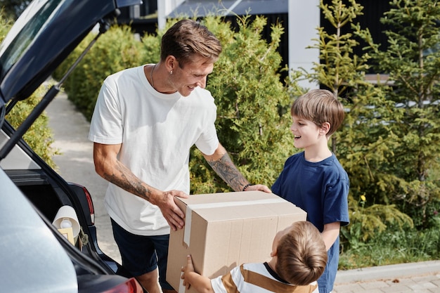 Padre con figli che trasportano scatole in auto