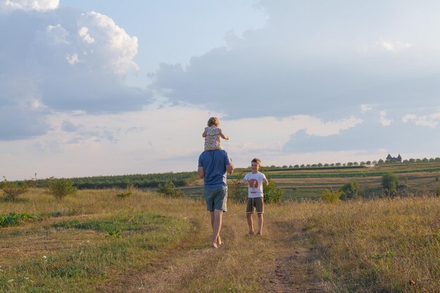 Padre con figli sulle spalle nella strada del villaggio Famiglia nella natura nel concetto di villaggio