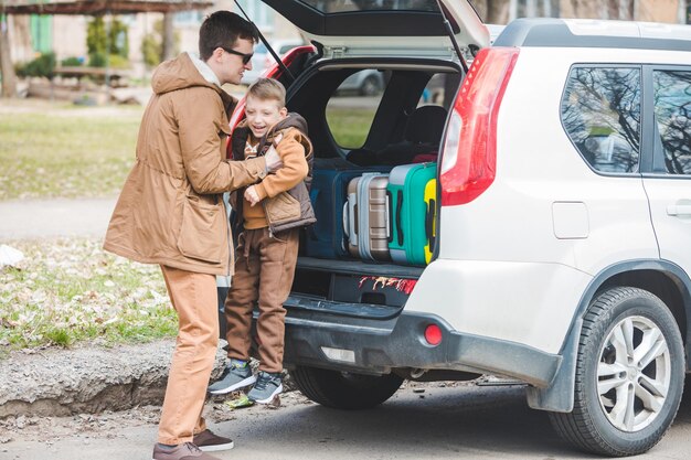 Padre con figlio che imballa i sacchetti per il concetto di viaggio in auto nel bagagliaio dell'auto