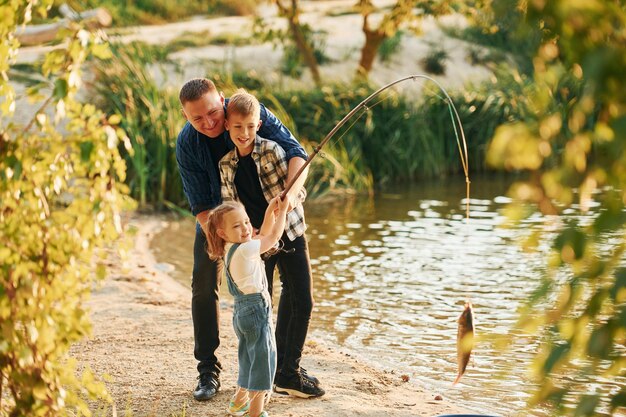 Padre con figlio e figlia che pescano insieme all'aperto in estate