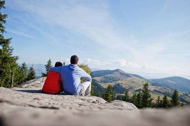 Padre con figlio. I bambini fanno un'escursione in una bella giornata in montagna, riposano sulla roccia e ammirano la splendida vista sulle cime delle montagne. Tempo libero attivo per le vacanze in famiglia con bambini. Divertimento all'aria aperta e attività salutari.