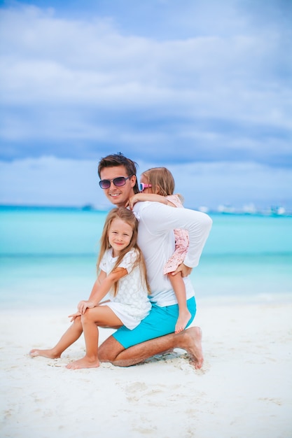 Padre con i bambini sulla spiaggia che gode dell'estate. Vacanze di famiglia