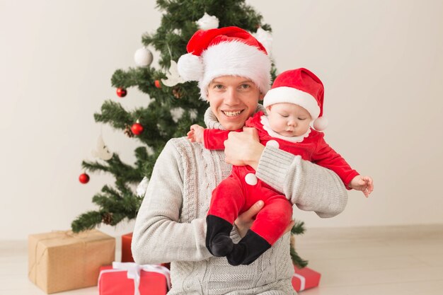 Padre con il suo bambino che indossa cappelli di Babbo Natale per celebrare il Natale.