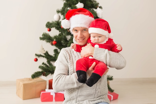 Padre con il suo bambino indossando cappelli di Babbo Natale per celebrare il Natale.