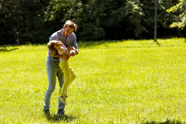 Padre con la figlia che si divertono sull'erba al parco