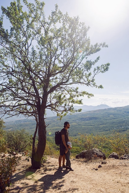 Padre con uno zaino e suo figlio si trova accanto a un albero su una montagna in estate in Crimea