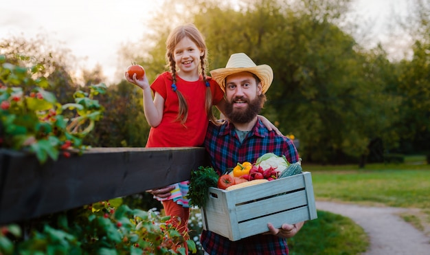 Padre della tenuta della bambina dei bambini un canestro delle verdure organiche fresche con il giardino domestico.