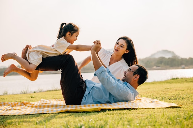 Padre di famiglia felice che tiene la figlia piccola sulle gambe dritte con la madre