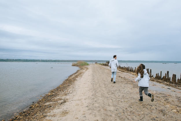 Padre e dauther si sono vestiti con un impermeabile che corre vicino al lago e si divertono