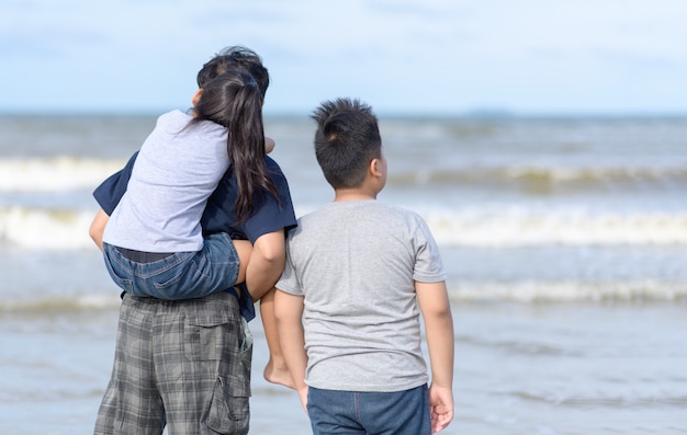 Padre e due bambini che camminano sulla spiaggia,