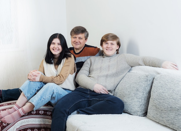 Padre e due figli adolescenti sul divano di casa