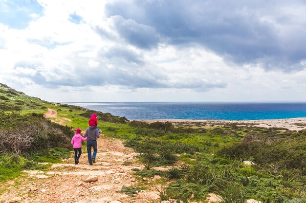 Padre e due figlie camminano lungo il sentiero lungo il mare Splendida valle in riva al mare Paesaggio marino a Cipro Ayia Napa
