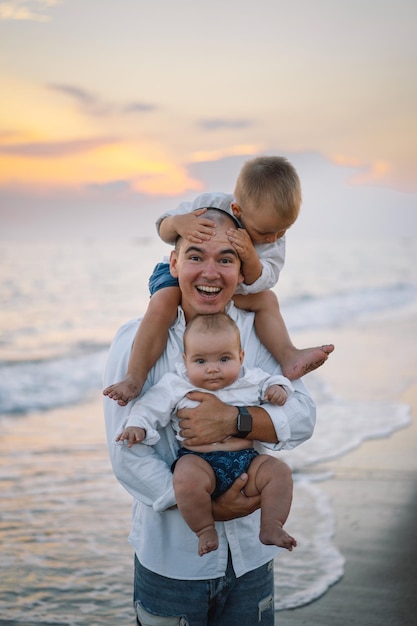 Padre e figli giocano sulla spiaggia Papà e lui Childs insieme si godono il tramonto