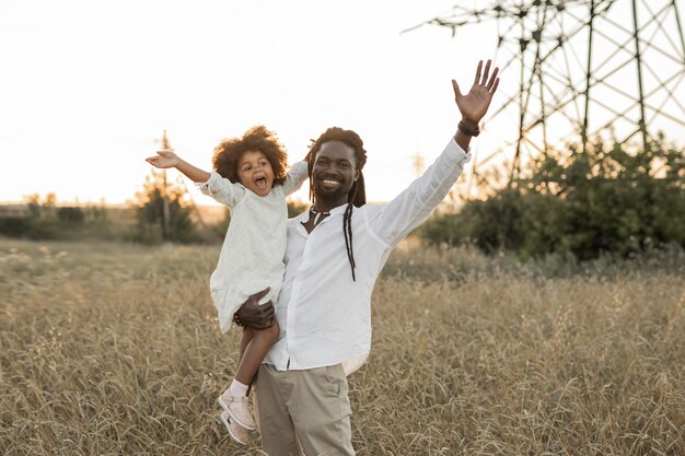 padre e figlia africani felici in una passeggiata estiva in un campo