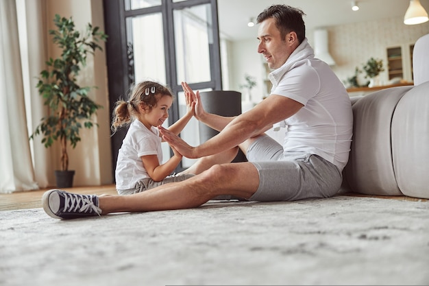 Padre e figlia allegri che giocano a pasticcini in casa