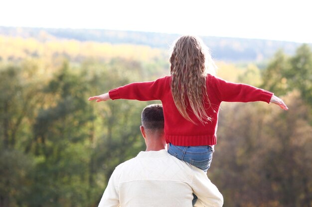 padre e figlia che camminano nel concetto di gioco del parco autunnale famiglia premurosa