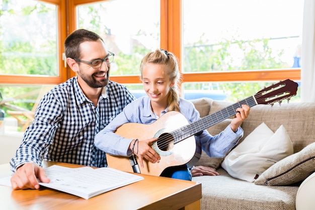 Padre e figlia che imparano a suonare la chitarra