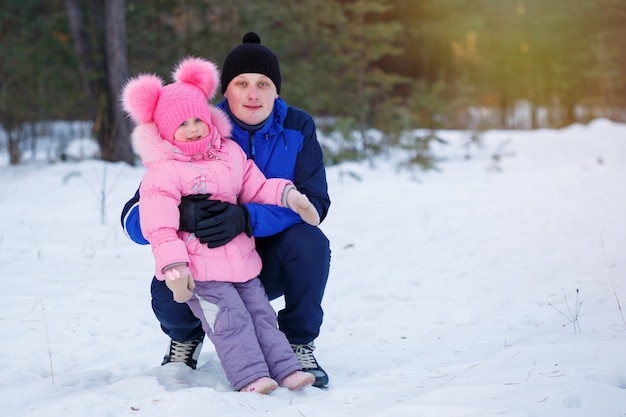 Padre e figlia che riposano nella foresta di inverno