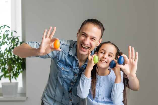 padre e figlia dipingono le uova con i colori. Divertiti. La famiglia felice si sta preparando per la Pasqua.