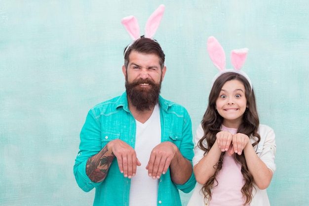 Padre e figlia in orecchie da coniglio a caccia di uova colorate il giorno di Pasqua Famiglia moderna che si prepara per la Pasqua felice pasqua divertente papà e bambina che indossano orecchie da coniglio caccia alle uova concetto spazio copia