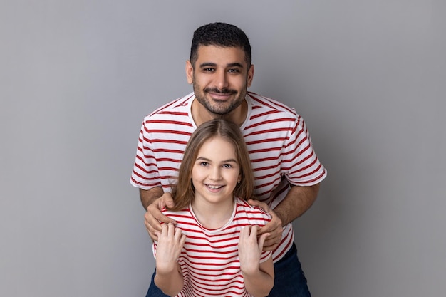 Padre e figlia in piedi e guardando la fotocamera papà che abbraccia il ragazzino che esprime felicità