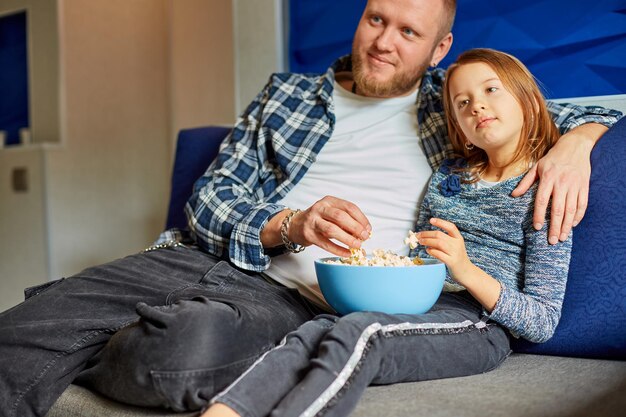 Padre e figlia mangiano popcorn e guardano film in TV