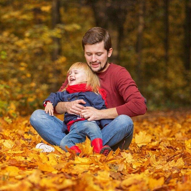 Padre e figlia si abbracciano e ridono nel parco autunnale