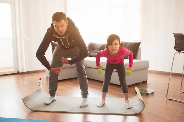 Padre e figlia si allenano a casa. Allenamento nell'appartamento.