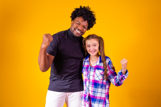 Padre e figlia su sfondo giallo che celebrano la vittoria Padre e figlia che fanno il segno di sì