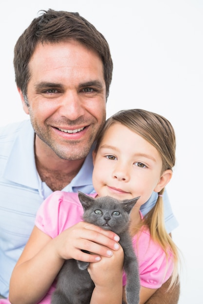 Padre e figlia svegli con il gattino dell&#39;animale domestico che sorridono insieme alla macchina fotografica