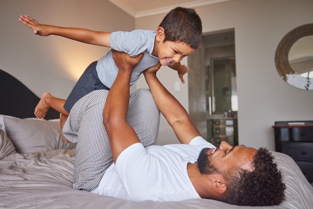 Padre e figlio a letto con giochi divertenti per lo sviluppo del bambino in camera da letto a casa e in casa al mattino Felice amore e cura di papà e bambino con immaginazione gioco creativo e felicità insieme