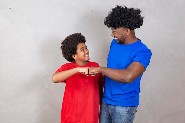 Padre e figlio afro che festeggiano su sfondo grigio felici per la festa del papà o la festa dei bambini