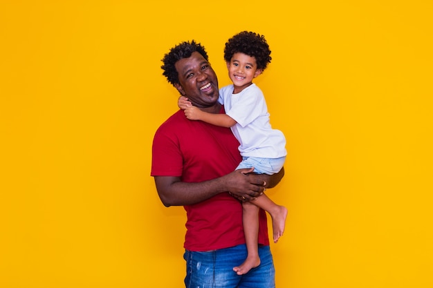 Padre e figlio afro su sfondo giallo sorridente. Concetto di festa del papà