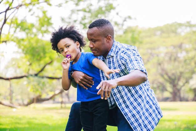 Padre e figlio afroamericani che giocano nel parco Concetto di festa del papà