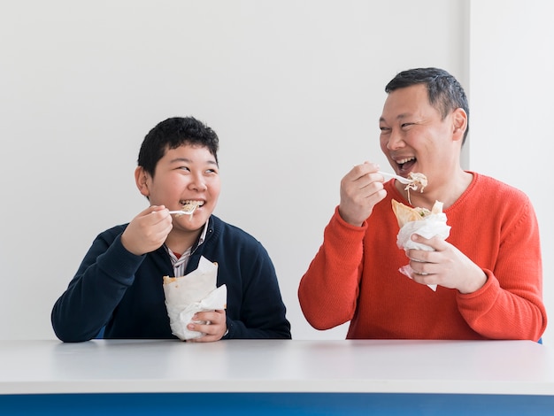 Padre e figlio asiatici che mangiano insieme