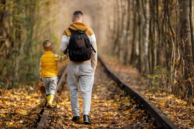 Padre e figlio camminano sulla ferrovia durante il viaggio Famiglia che trascorrono del tempo insieme in vacanza padre e figlio trascorrono del tempo insieme in autunno