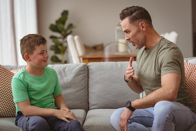 Padre e figlio caucasici comunicano usando il linguaggio dei segni mentre sono seduti sul divano di casa