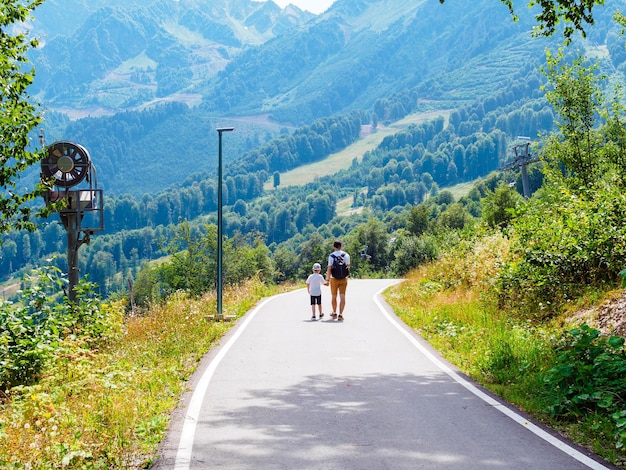 Padre e figlio che camminano lungo la strada in montagna