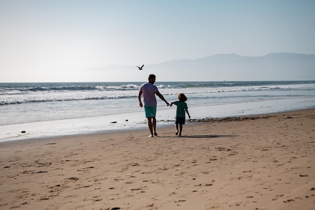 Padre e figlio che camminano sul mare Papà e figlio si tengono per mano e camminano insieme