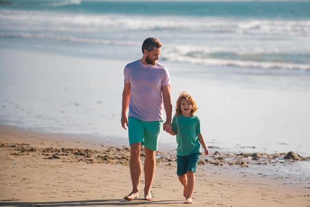 Padre e figlio che camminano sulla spiaggia estiva infanzia e concetto di genitorialità