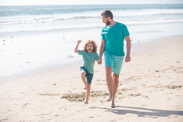 Padre e figlio che corrono sulla spiaggia estiva papà e bambino che giocano all'aperto