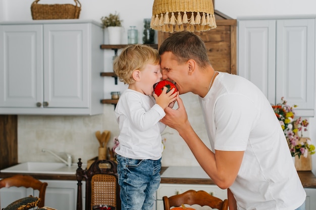 Padre e figlio che cucinano insieme nella cucina alla moda. Figlio e papà mordono insieme.