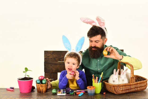 Padre e figlio che dipingono le uova di pasqua bambino carino che indossa orecchie da coniglio il giorno di pasqua