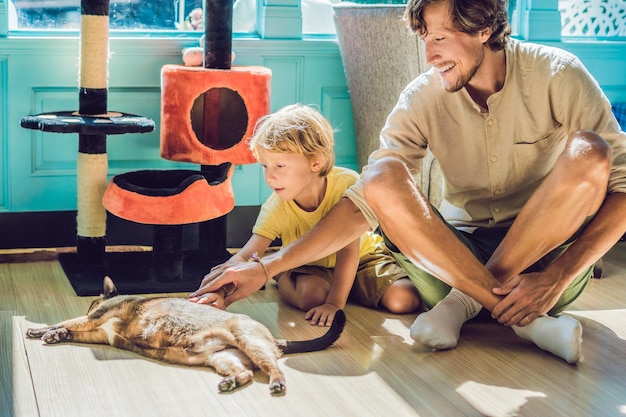 Padre e figlio che giocano con un gatto.