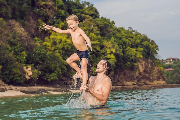 Padre e figlio che giocano sulla spiaggia durante il giorno